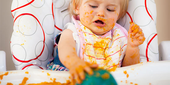 little girl meesing up her plate of food