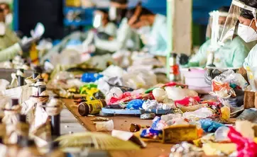 Muncitori sortand materiale reciclabile intr-o fabrica de procesare
